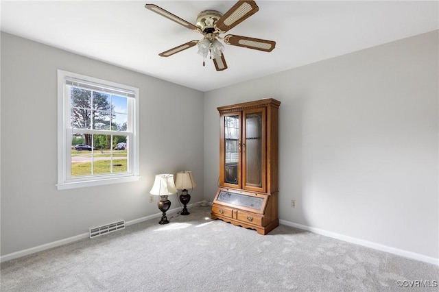 carpeted spare room featuring baseboards, visible vents, and a ceiling fan