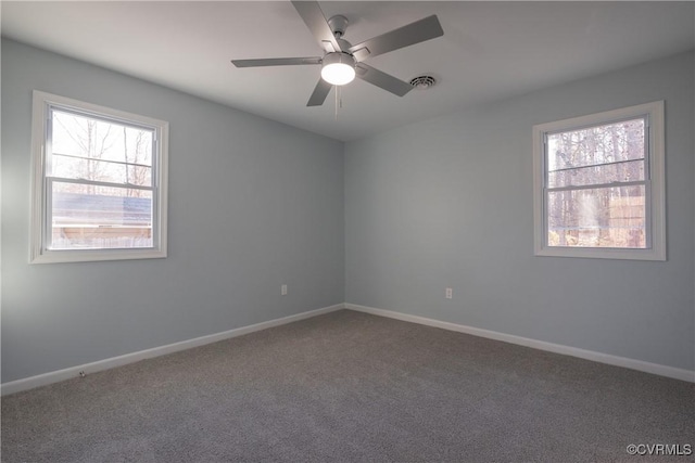 carpeted empty room with a wealth of natural light, visible vents, a ceiling fan, and baseboards