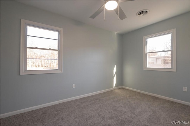 carpeted empty room with baseboards, visible vents, ceiling fan, and plenty of natural light
