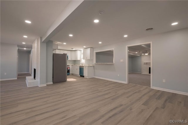 unfurnished living room with a fireplace, recessed lighting, light wood-style flooring, and baseboards