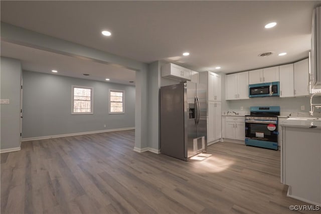kitchen featuring appliances with stainless steel finishes, wood finished floors, and white cabinetry
