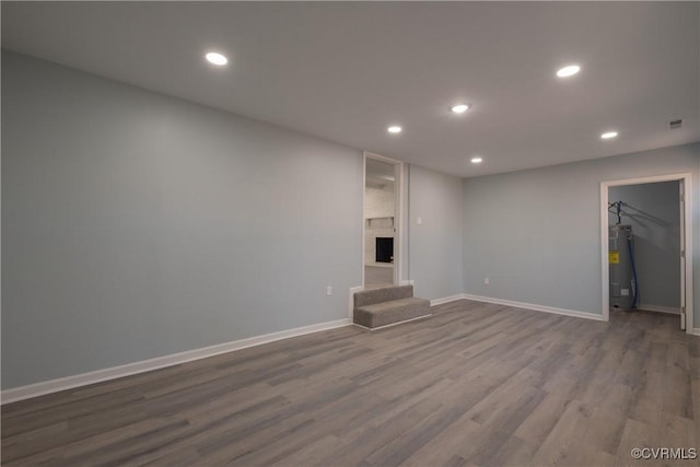 unfurnished living room with baseboards, recessed lighting, water heater, and dark wood-style flooring