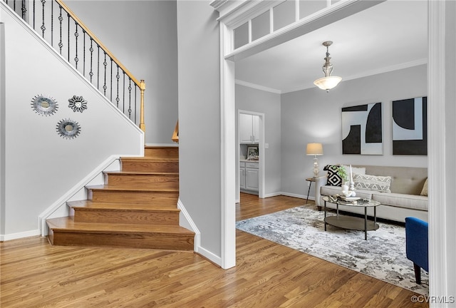 staircase with crown molding, wood finished floors, and baseboards