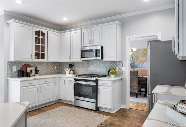 kitchen with appliances with stainless steel finishes, backsplash, white cabinets, glass insert cabinets, and crown molding