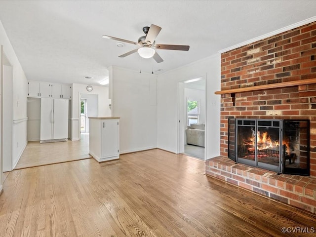 10811 Shady Ln, Charles City, VA 23030 - unfurnished living room with light wood-type flooring, a ceiling fan, a brick fireplace, and baseboards