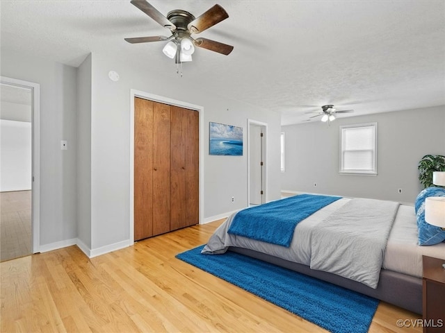 10811 Shady Ln, Charles City, VA 23030 - bedroom featuring light wood-style flooring, a textured ceiling, a ceiling fan, baseboards, and a closet