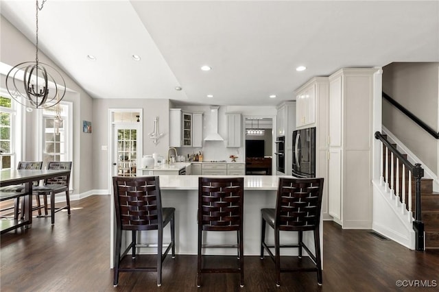 kitchen with light countertops, a kitchen breakfast bar, a notable chandelier, and black refrigerator with ice dispenser