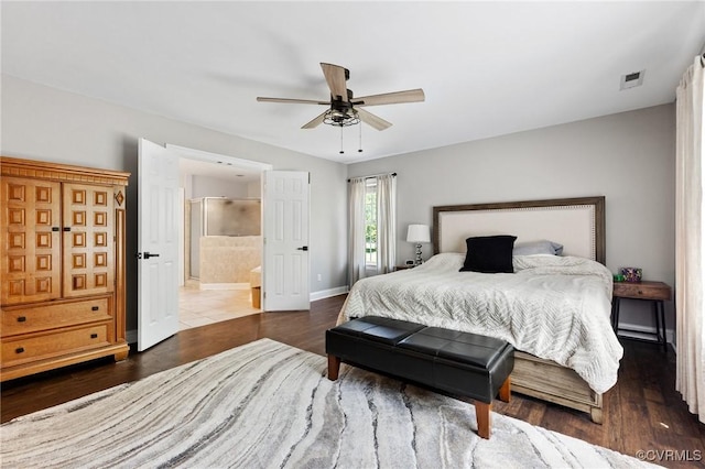bedroom featuring a ceiling fan, visible vents, wood finished floors, baseboards, and ensuite bathroom