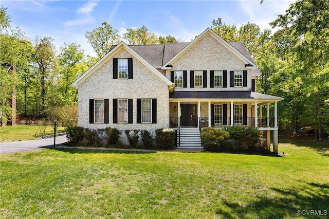 traditional home featuring covered porch, brick siding, and a front lawn