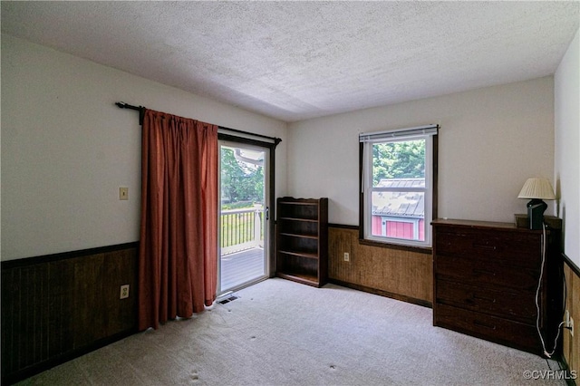 10 Mahon, Ruther Glen, VA 22546 - carpeted bedroom featuring access to outside, a wainscoted wall, multiple windows, a textured ceiling, and wood walls