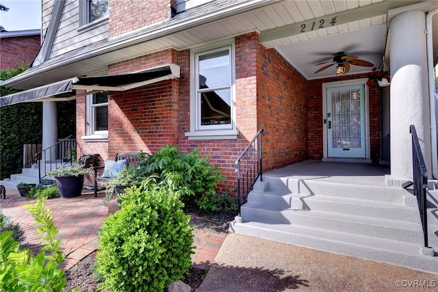 property entrance with a ceiling fan and brick siding