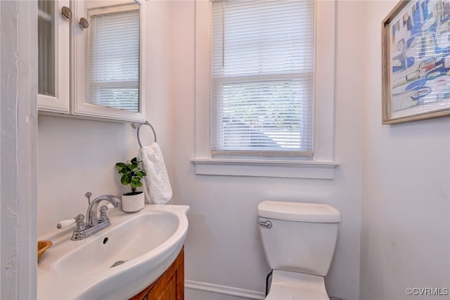 half bathroom featuring vanity, toilet, and baseboards