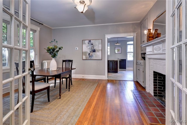 dining room with crown molding, baseboards, light wood-style flooring, and a fireplace