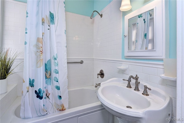 full bath with shower / bath combo with shower curtain, tile walls, and a sink
