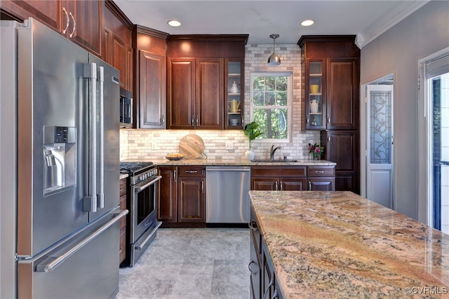 kitchen featuring a healthy amount of sunlight, stainless steel appliances, light stone countertops, and a sink