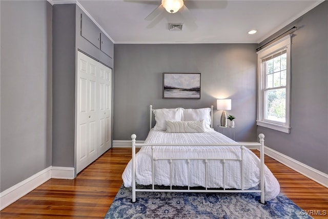 bedroom featuring wood finished floors, visible vents, crown molding, and baseboards