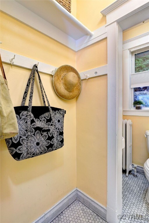 mudroom with tile patterned floors, baseboards, and radiator