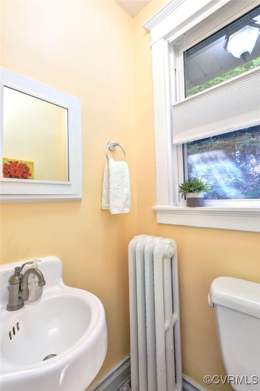 half bath featuring a sink, toilet, and radiator