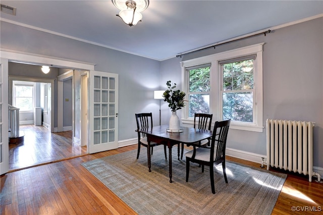 dining room featuring visible vents, ornamental molding, wood-type flooring, and radiator