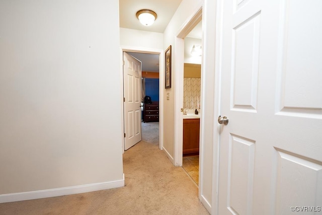 hallway featuring light carpet and baseboards
