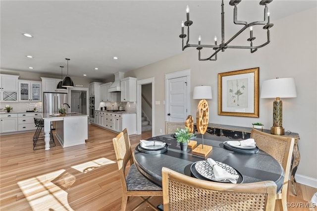 dining room featuring recessed lighting, stairs, light wood finished floors, baseboards, and a notable chandelier