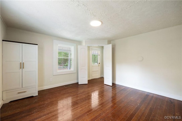 unfurnished bedroom with a textured ceiling, hardwood / wood-style floors, and baseboards
