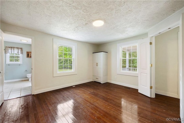unfurnished bedroom with baseboards, visible vents, hardwood / wood-style flooring, and a textured ceiling