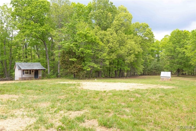 view of yard with a storage unit, an outdoor structure, and a forest view