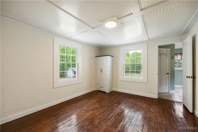 unfurnished room featuring baseboards, visible vents, a wealth of natural light, and dark wood-type flooring