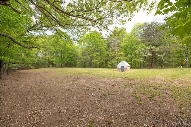 view of yard with an outbuilding, a shed, and a view of trees