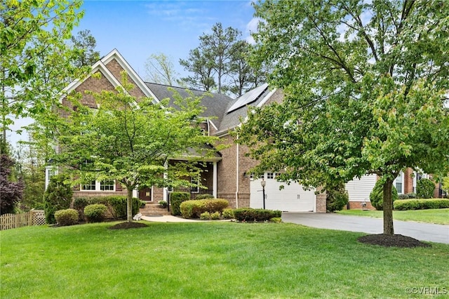 view of front of home featuring a front lawn, a garage, driveway, brick siding, and fence
