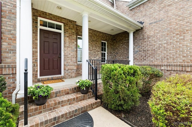 property entrance with a porch and brick siding
