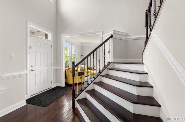 entrance foyer featuring hardwood / wood-style floors, baseboards, stairs, and a towering ceiling