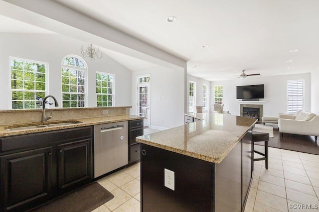 kitchen with stainless steel dishwasher, a sink, light tile patterned floors, and a fireplace