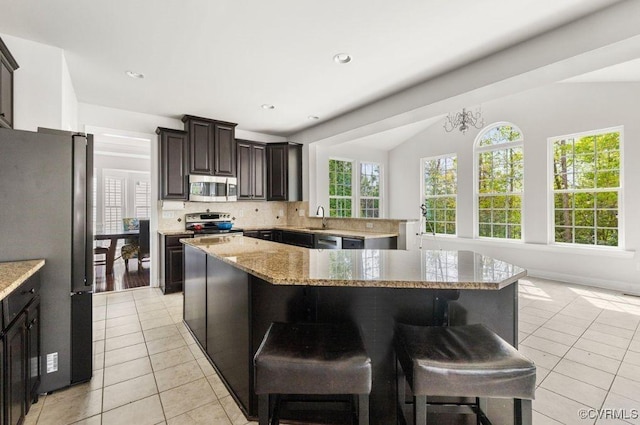 kitchen featuring a breakfast bar area, light tile patterned floors, stainless steel appliances, and tasteful backsplash