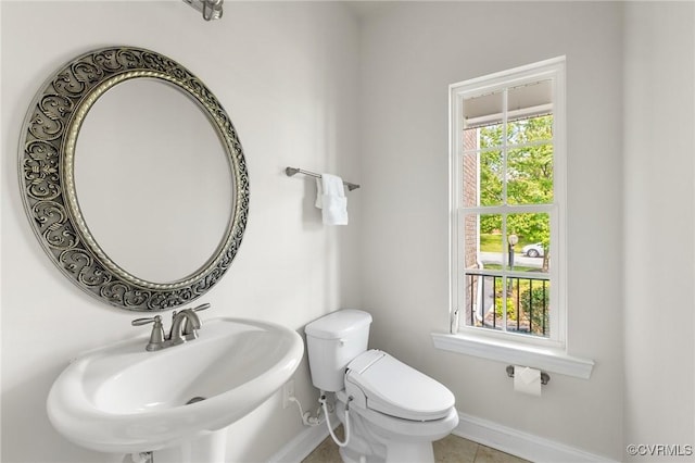 bathroom with toilet, baseboards, tile patterned flooring, and a sink