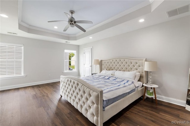 bedroom with ornamental molding, wood finished floors, visible vents, and a tray ceiling