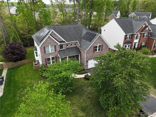 view of front of property with roof mounted solar panels, fence, brick siding, and a garage