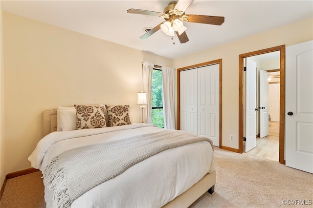 bedroom with light colored carpet, baseboards, ceiling fan, and a closet