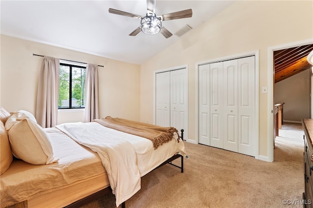 bedroom with multiple closets, visible vents, vaulted ceiling, and light colored carpet