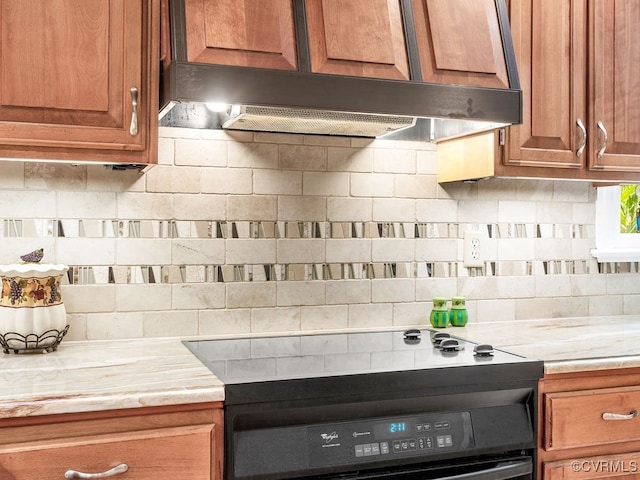 1735 Old Powhatan Ests, Powhatan, VA 23139 - kitchen with range with electric stovetop, backsplash, brown cabinets, light stone counters, and under cabinet range hood
