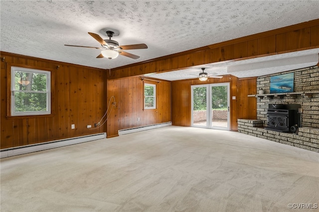 13101 Harrowgate Rd, Chester, VA 23831 - unfurnished living room featuring a baseboard radiator, a ceiling fan, a wood stove, carpet floors, and wood walls