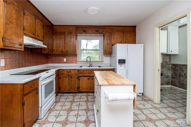 kitchen with white appliances, under cabinet range hood, light flooring, and a sink