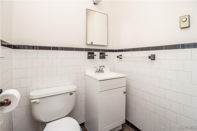 bathroom featuring tile walls, toilet, vanity, and wainscoting