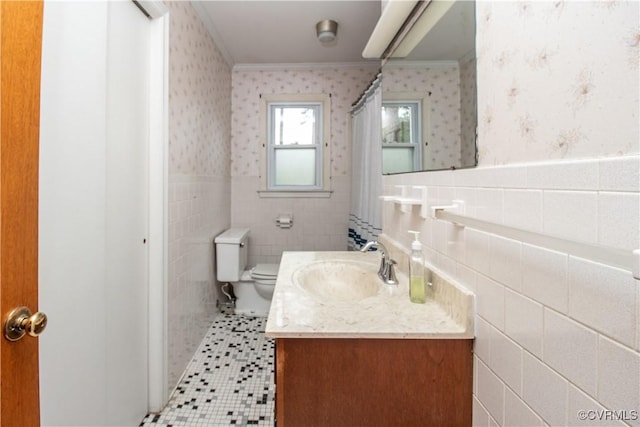 full bath with crown molding, wallpapered walls, tile walls, toilet, and a wainscoted wall
