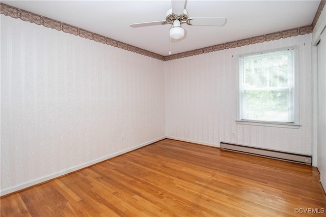 empty room with baseboard heating, light wood-type flooring, baseboards, and a ceiling fan