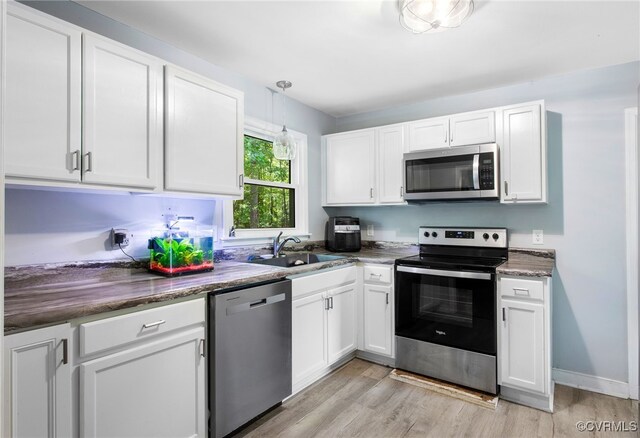 kitchen with appliances with stainless steel finishes, a sink, white cabinetry, and light wood-type flooring