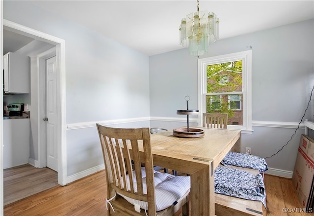 dining area with a chandelier, light wood-type flooring, and baseboards