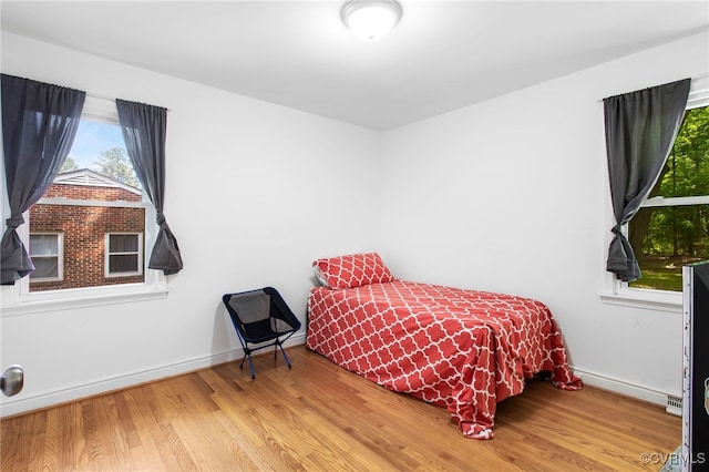 bedroom featuring wood finished floors, multiple windows, and baseboards
