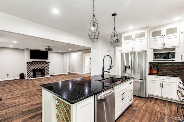 9073 Pine Hill Rd, Mechanicsville, VA 23116 - kitchen featuring appliances with stainless steel finishes, dark wood finished floors, tasteful backsplash, a center island with sink, and white cabinetry